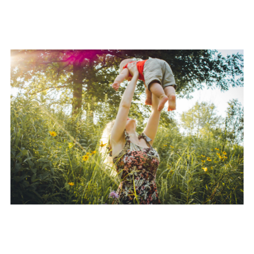 woman lifting her child up over her head outdoors